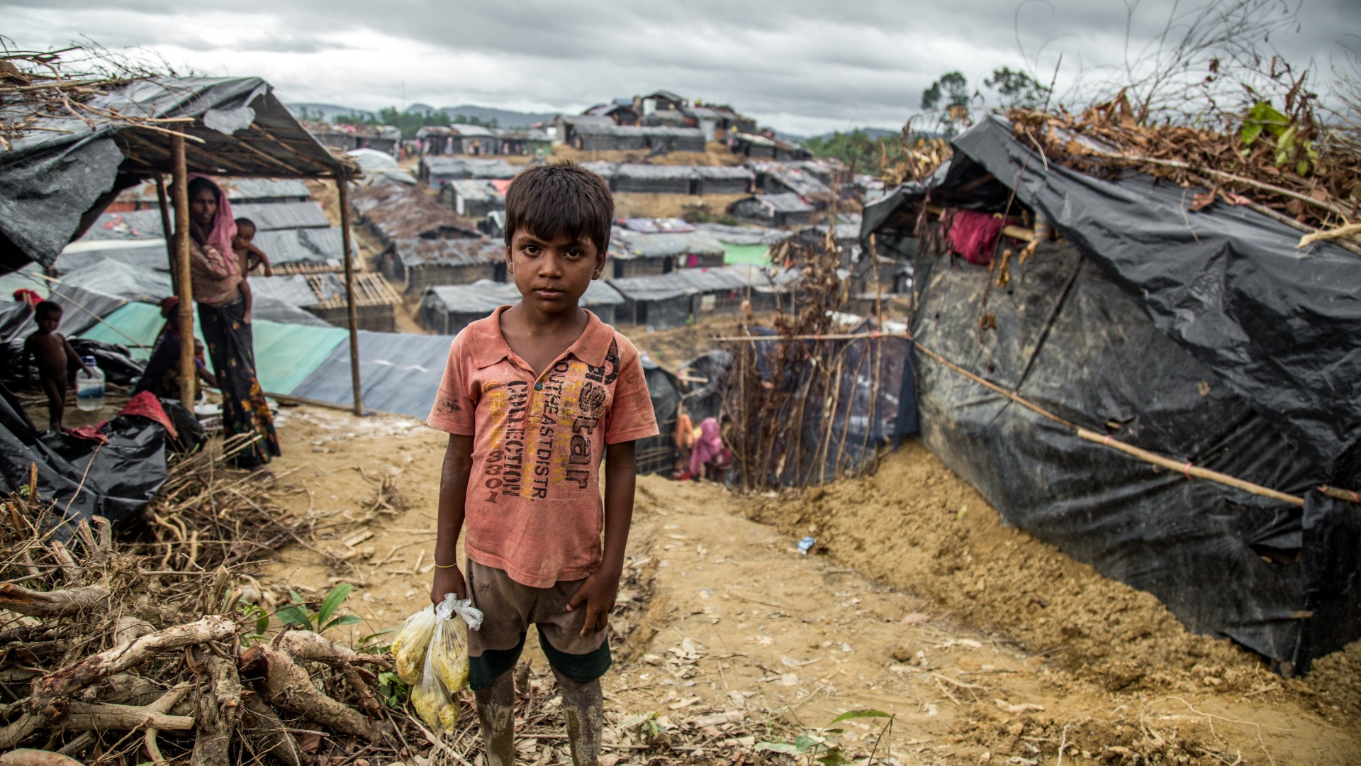 Muk Kashim, aged 8, holds bags of food aid in Cox's Bazar, Bangladesh