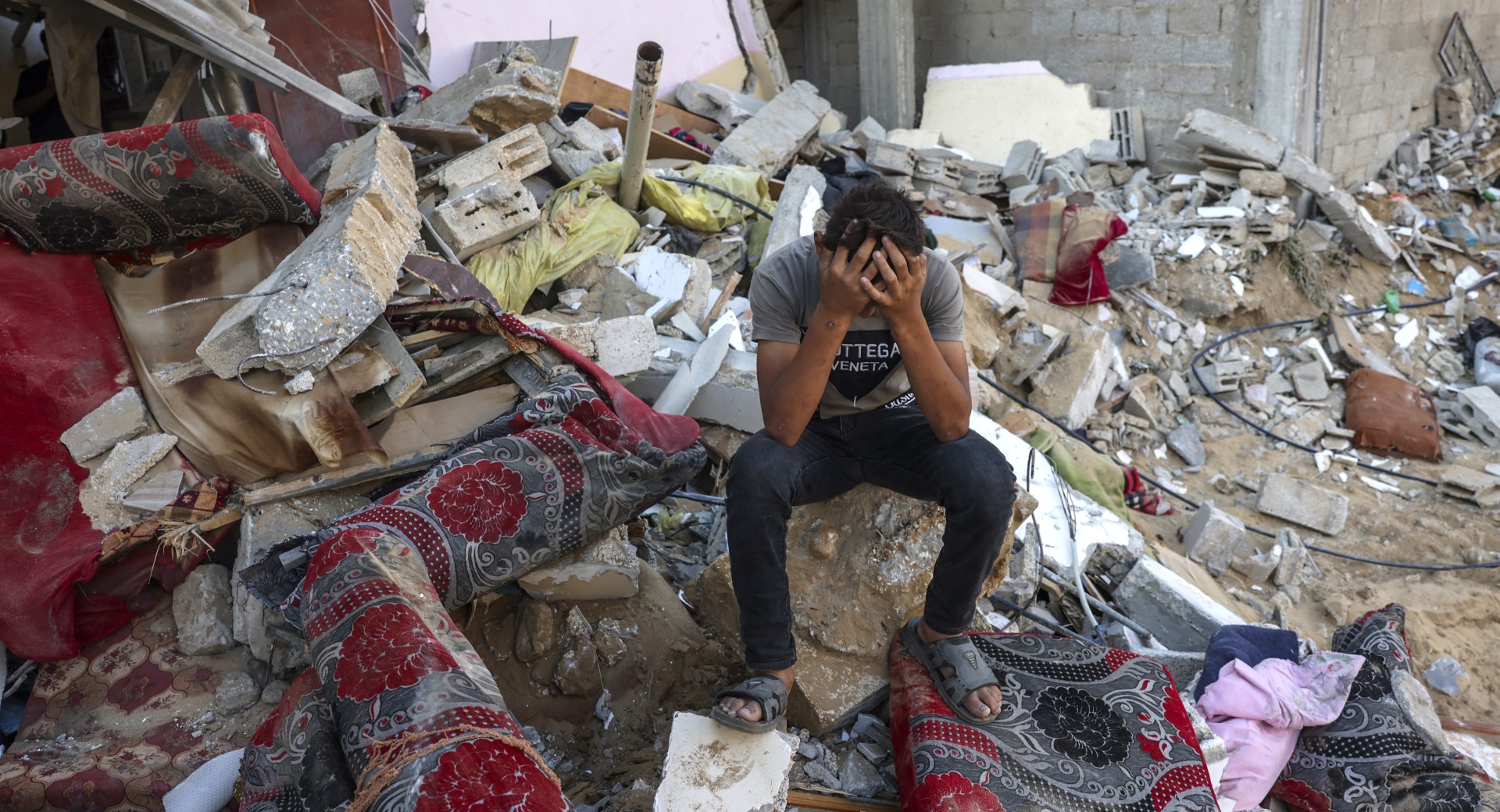 A Palestinian youth sits on the rubble of a destroyed home in the southern Gaza.