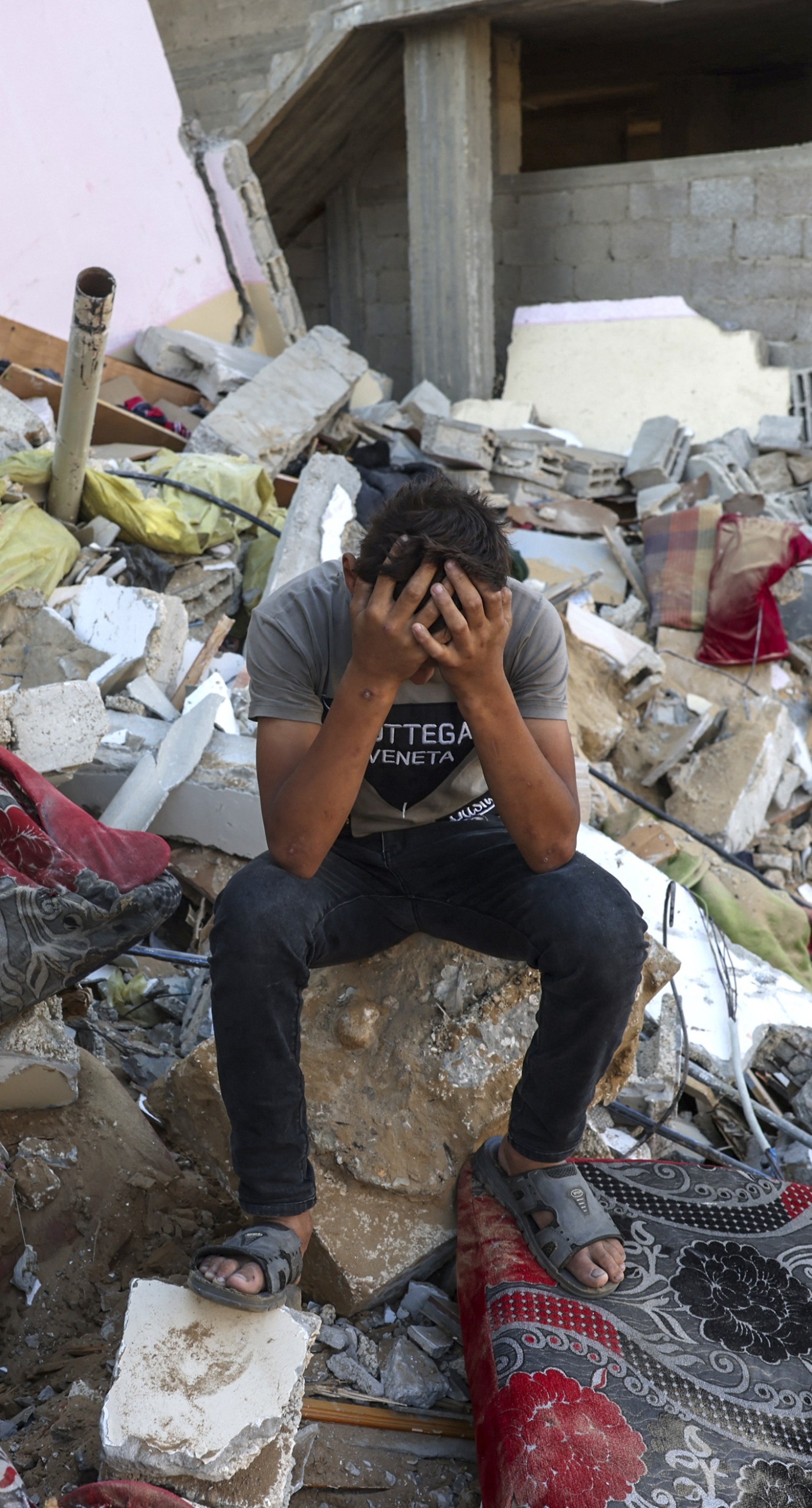 A Palestinian youth sits on the rubble of a destroyed home in the southern Gaza.