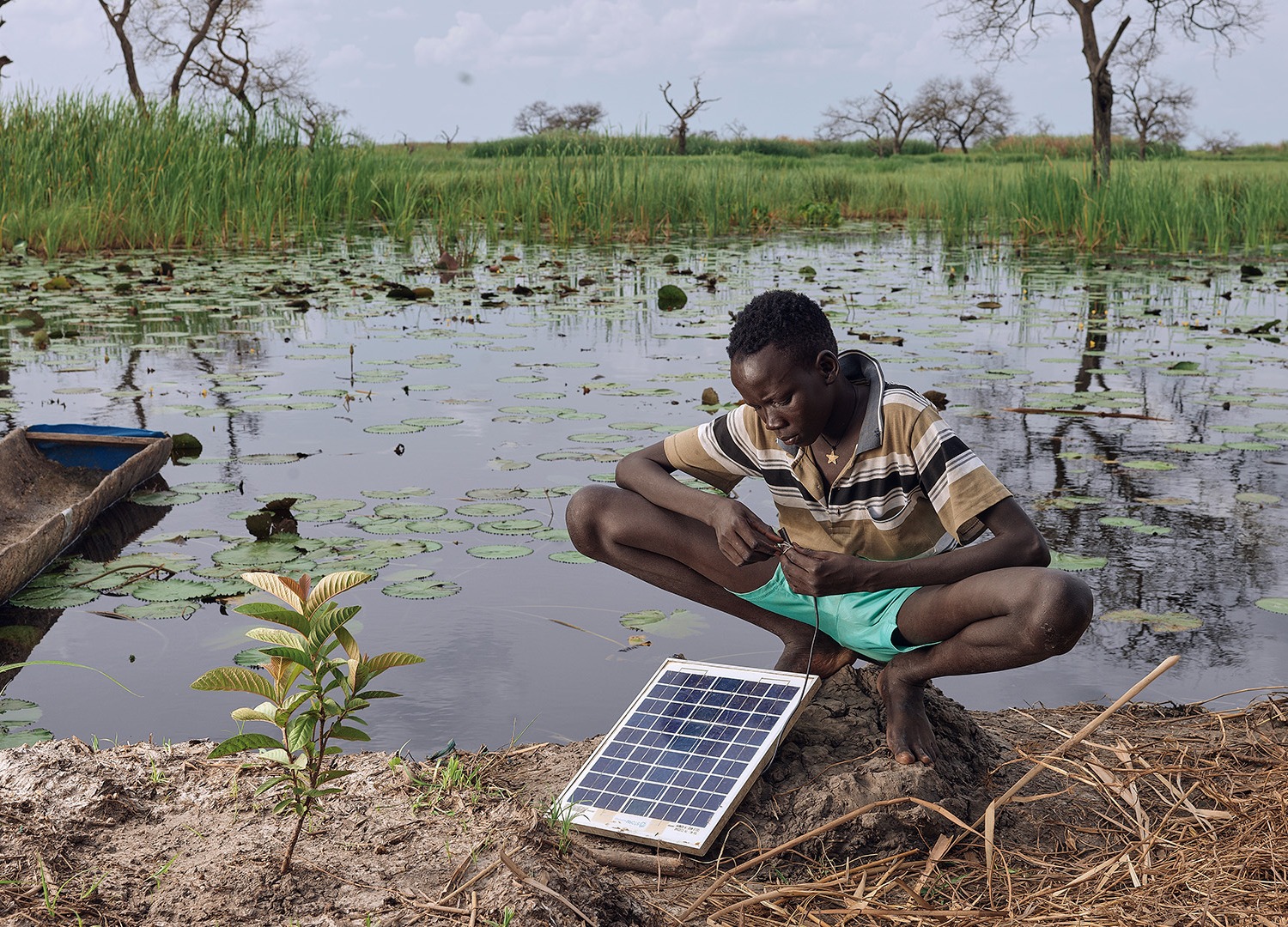 Gatwal Nhial repairs a solar panel which is their only source of power on his floating grass island in what used to be Wangkotha Village.