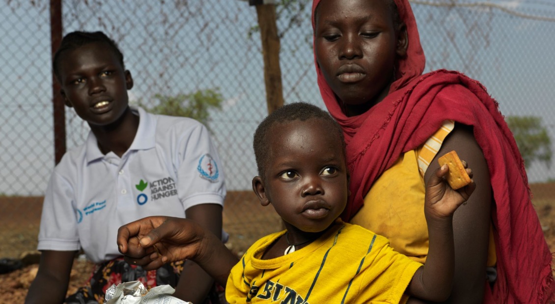 A woman holding a child eating crackers in South Sudan