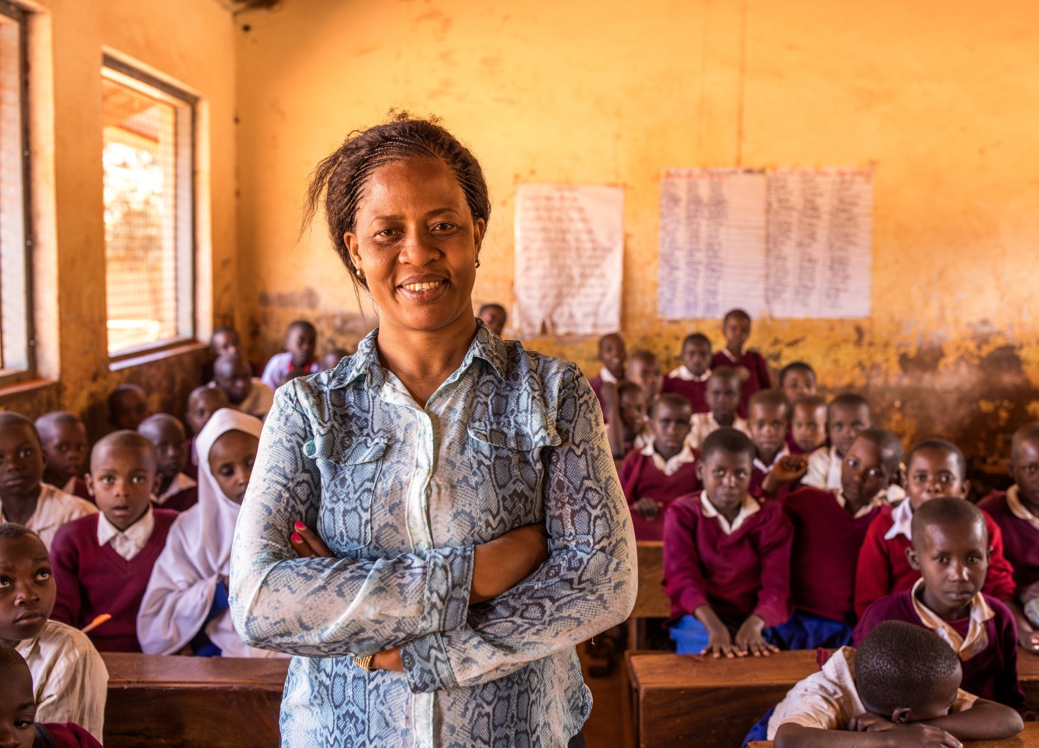 A proud teacher in front of a full classroom in Tanzania.