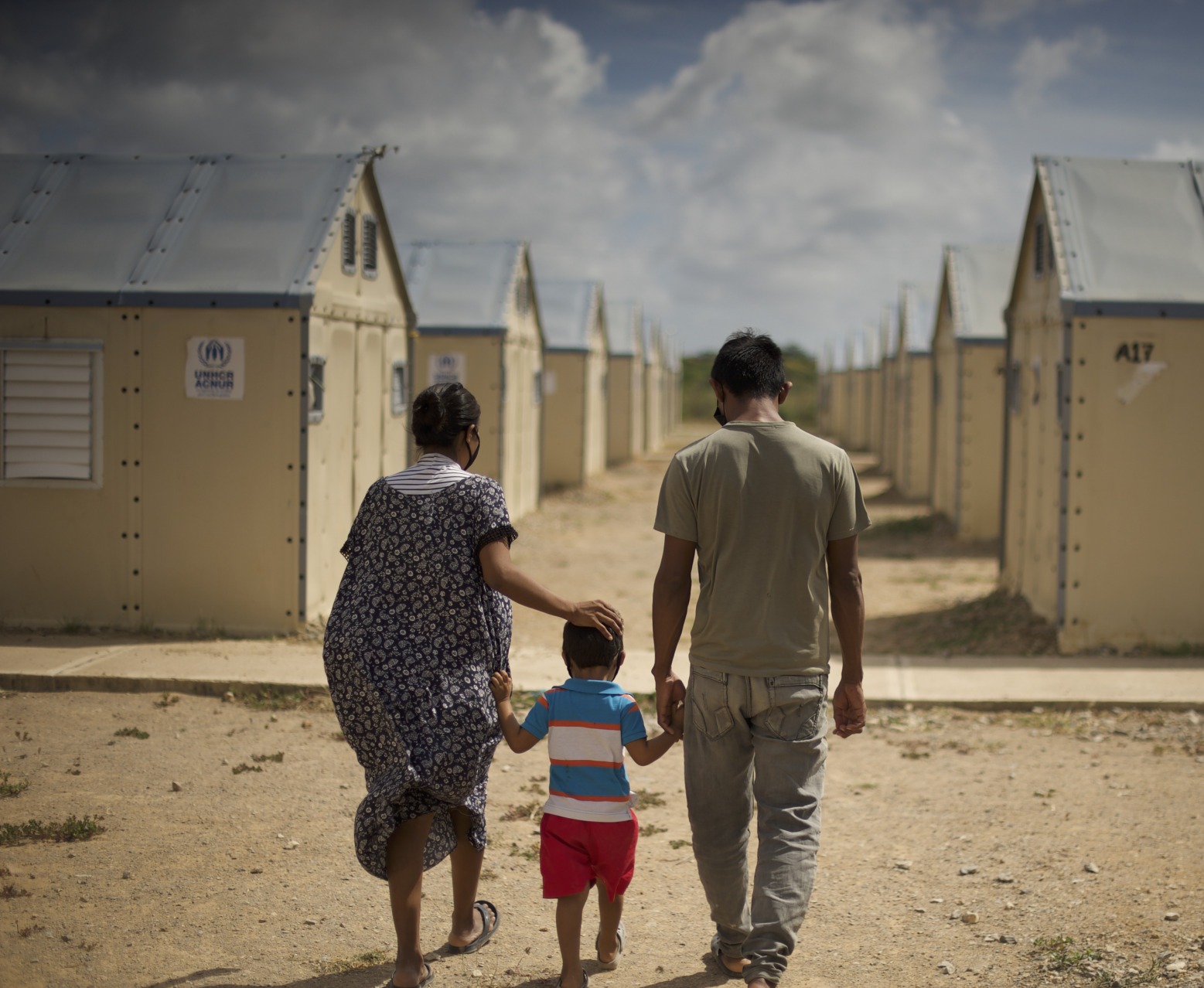 A family displaced by conflict walks through a settlement. Action Against Hunger is supporting families like these with cash transfers to help them buy food, medicine, and other goods.