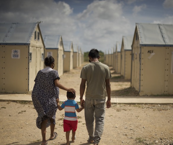 A family displaced by conflict walks through a settlement. Action Against Hunger is supporting families like these with cash transfers to help them buy food, medicine, and other goods.