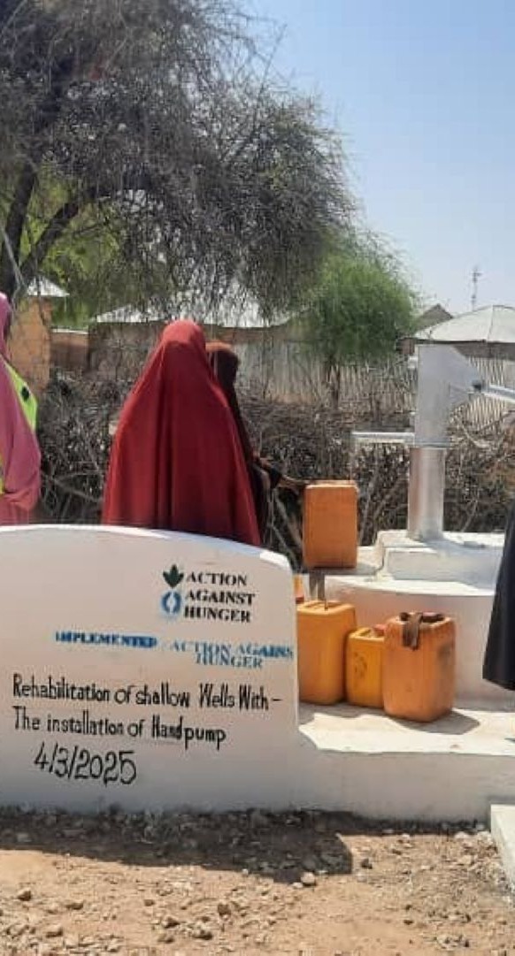 Community members drawing water from the rehabilitated well