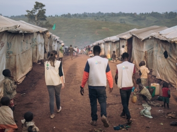 Action Against Hunger staff walk through Rhoe displacement camp.