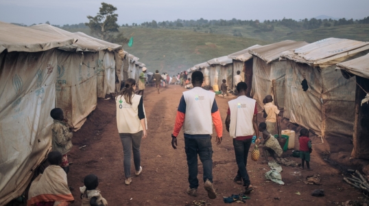 Action Against Hunger staff walk through Rhoe displacement camp.