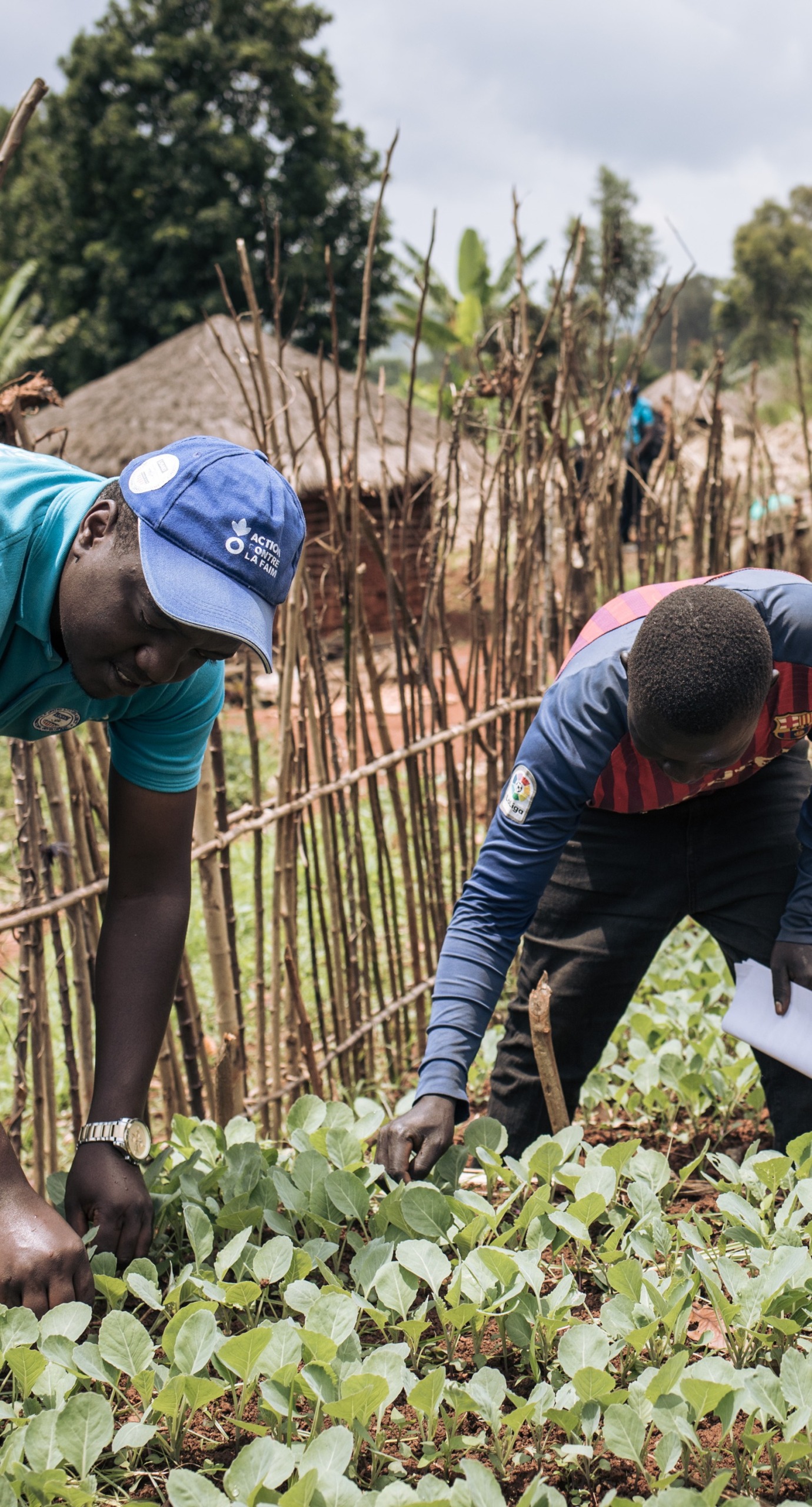 An Action Against Hunger aid workers teaches a farmer skills to help his crops grow.