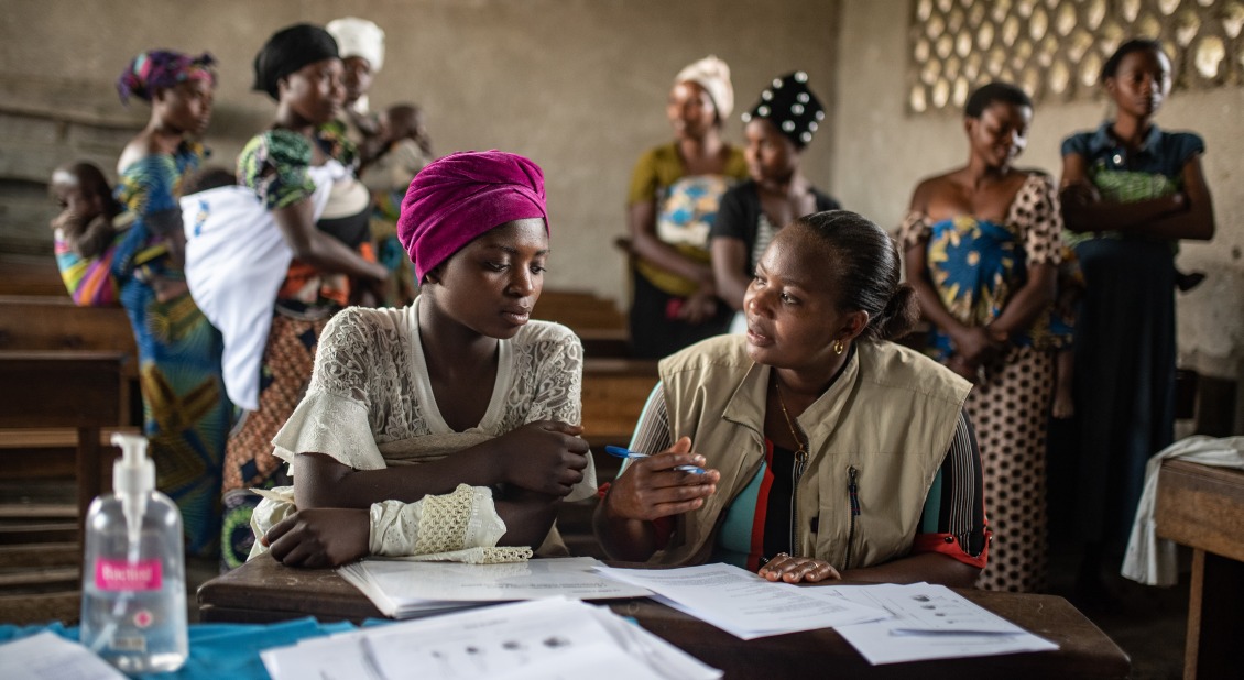 Action Against Hunger staff member sits with a woman in Democratic Republic of Congo