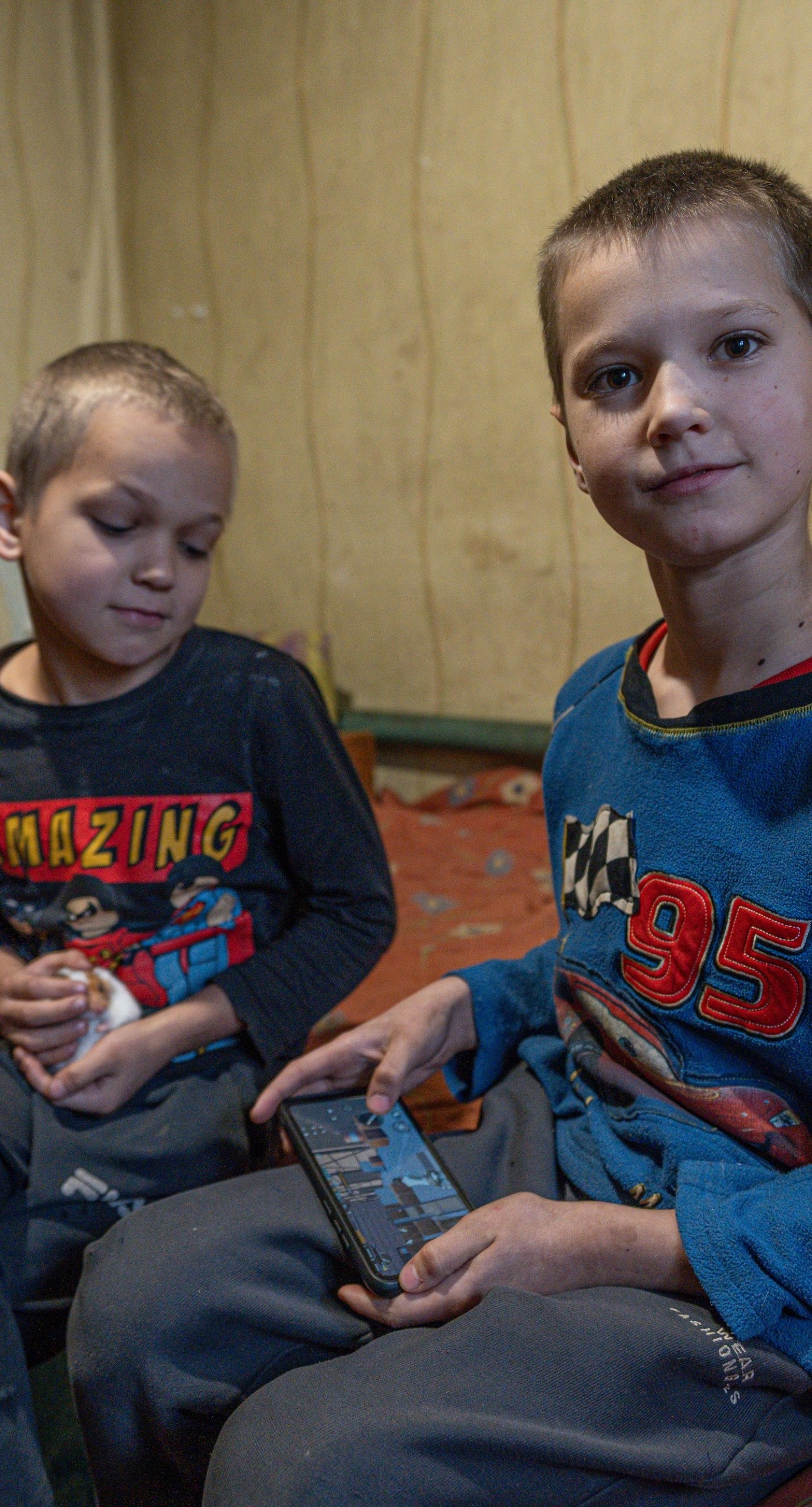 Two Ukrainian children sitting on a bed.