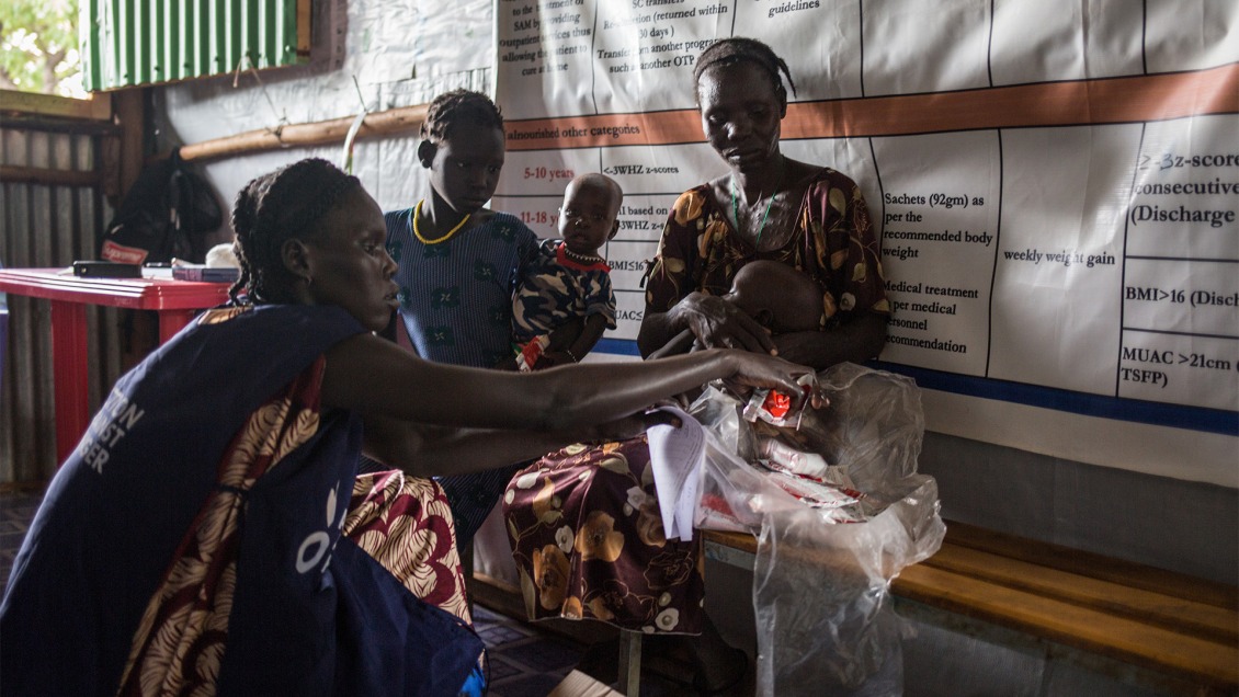 In Ethiopia, an ACF health worker distributes RUTF to two children.