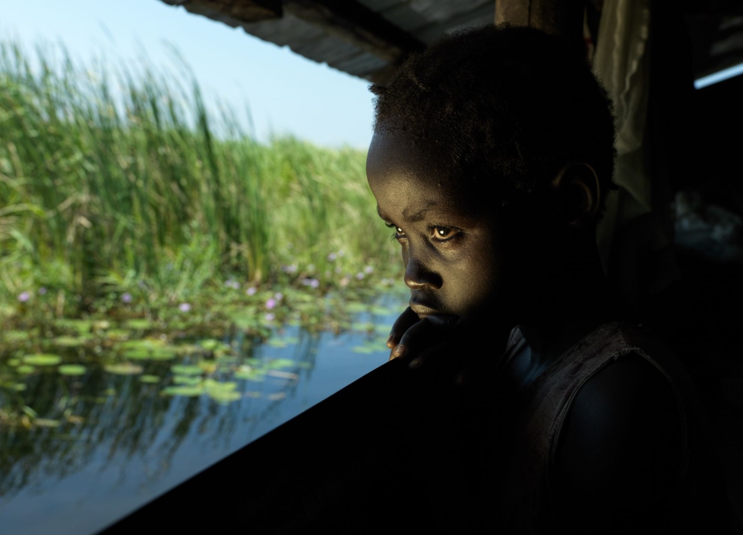 A child looking out of the house at flooding in South Sudan