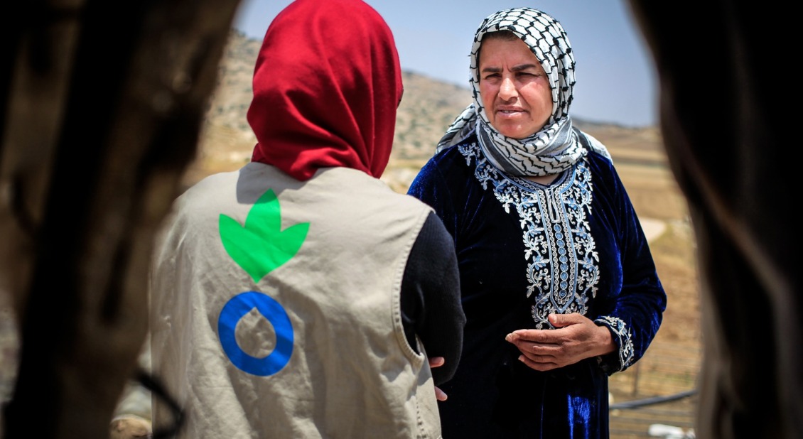 An Action Against Hunger aid worker talks with a Palestinian woman.