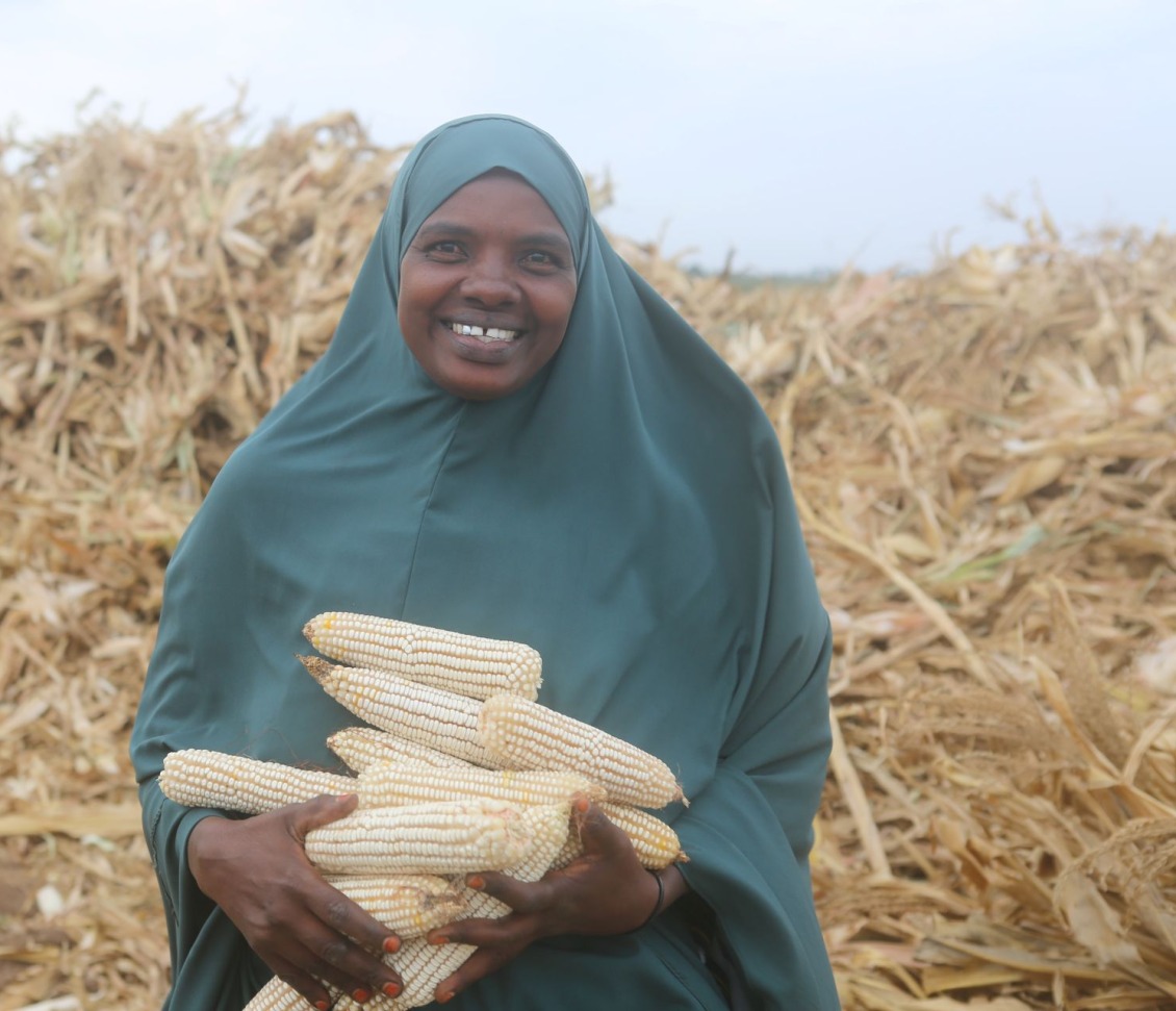 Halima, a member of the farming cooperative, holds her corn harvest.