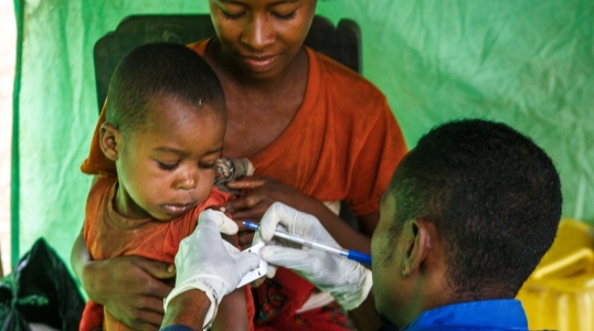 In Madagascar, an Action Against Hunger staff member uses a Mid-Upper Arm Circumference (MUAC) band to check a child for malnutrition.