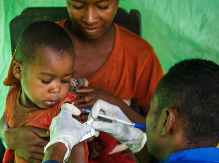 In Madagascar, an Action Against Hunger staff member uses a Mid-Upper Arm Circumference (MUAC) band to check a child for malnutrition.