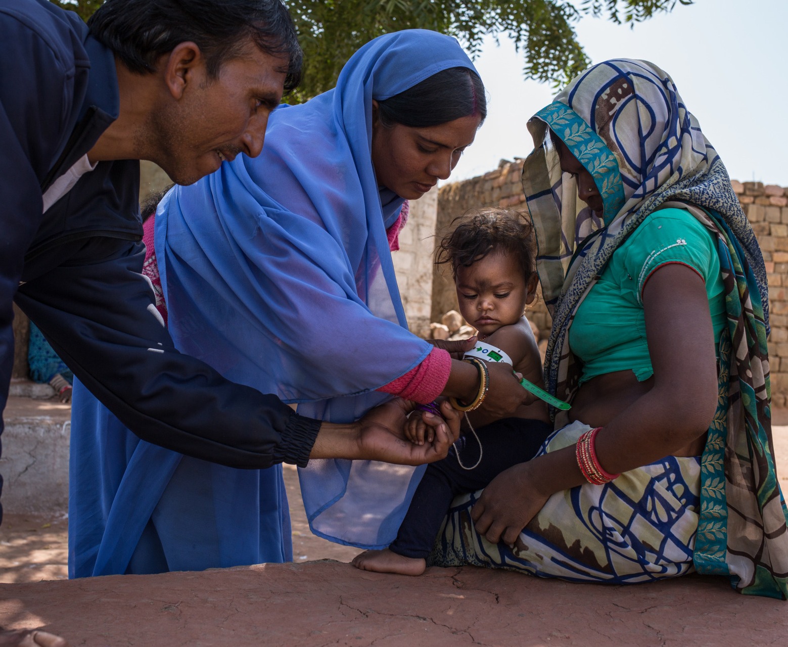 A community health worker shows a mother how to measure her child's nutrition status.