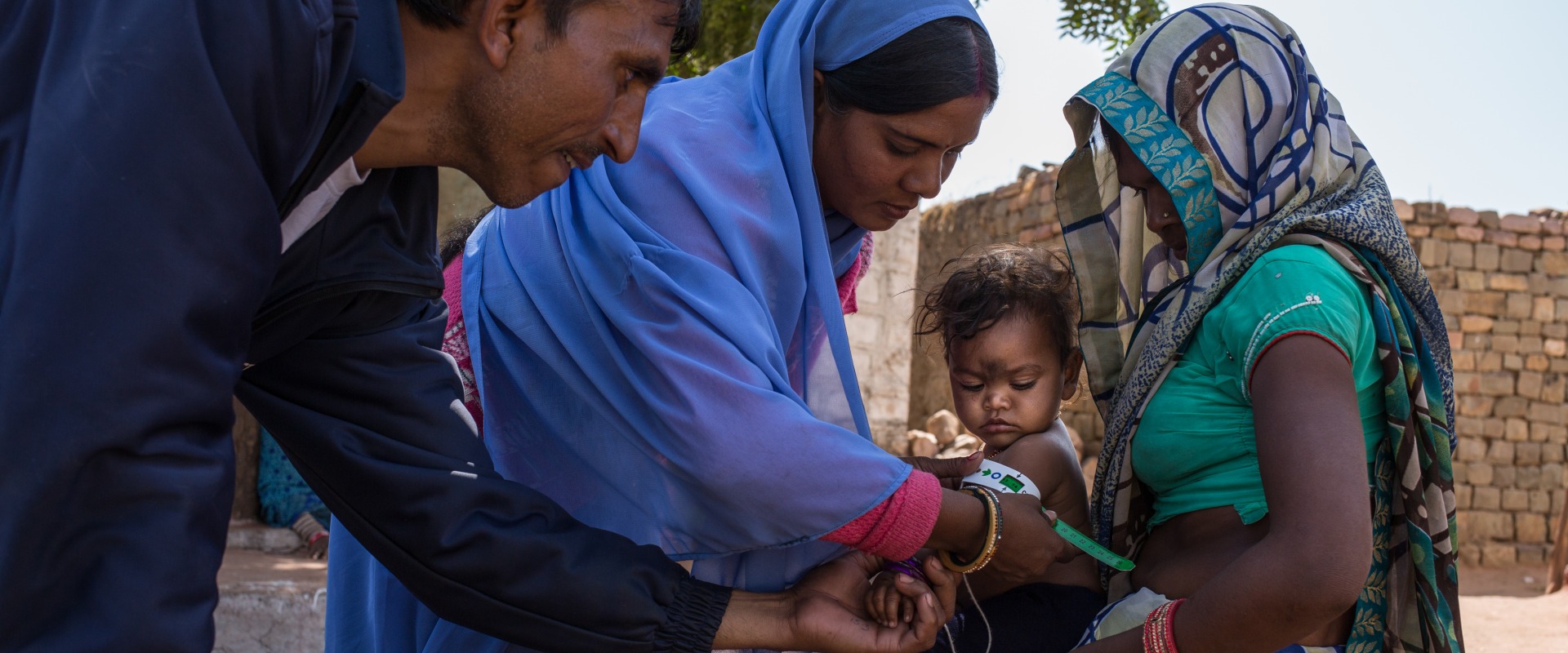 A community health worker shows a mother how to measure her child's nutrition status.