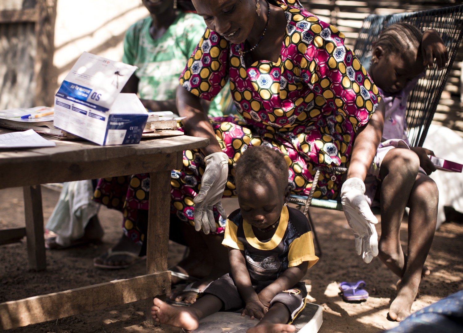 Hawa, an Action Against Hunger-trained community health worker, weighs a child as a part of a routine health check up.