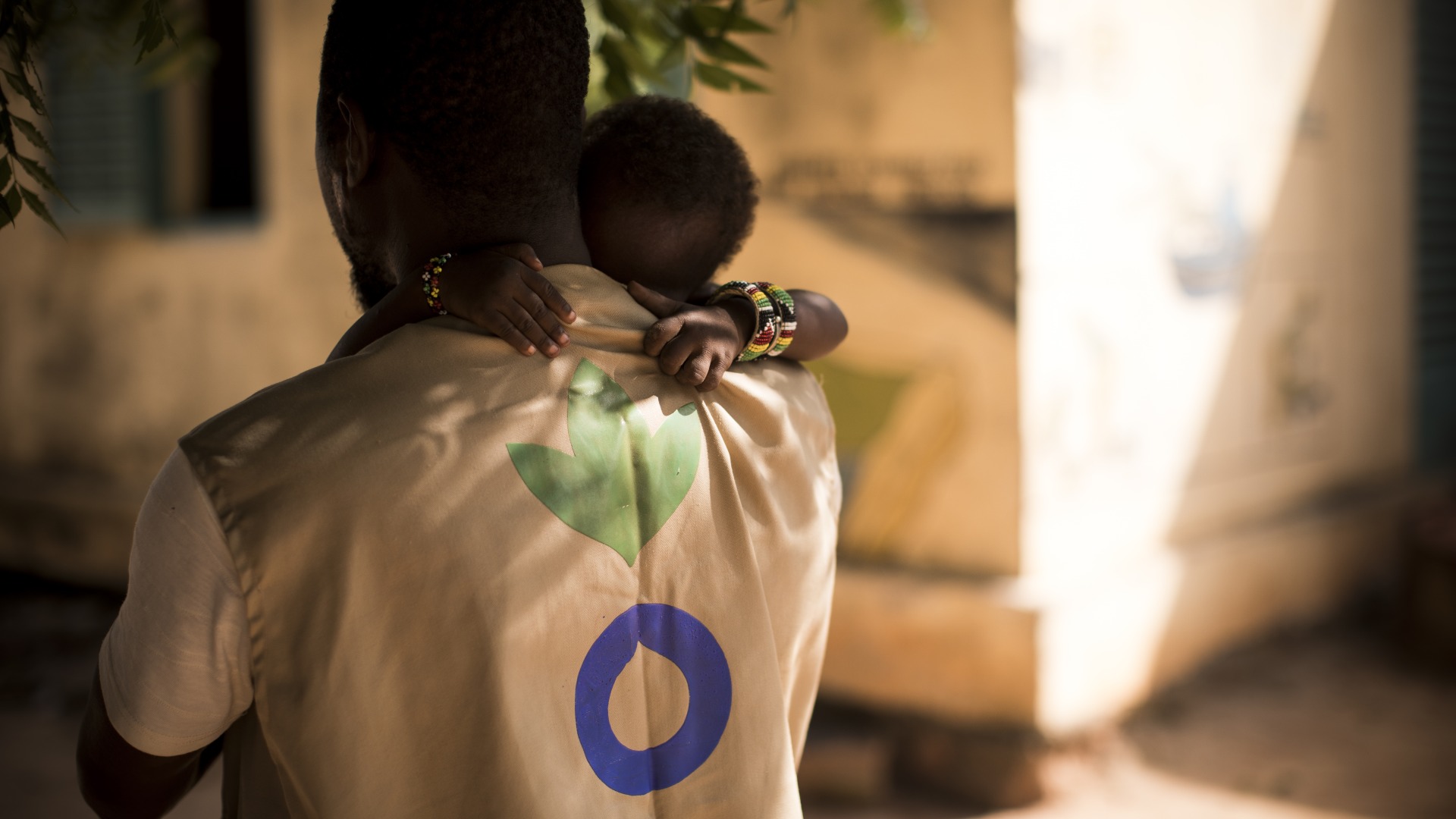 An Action Against Hunger Aid Worker holds a child in his arms in Mali.