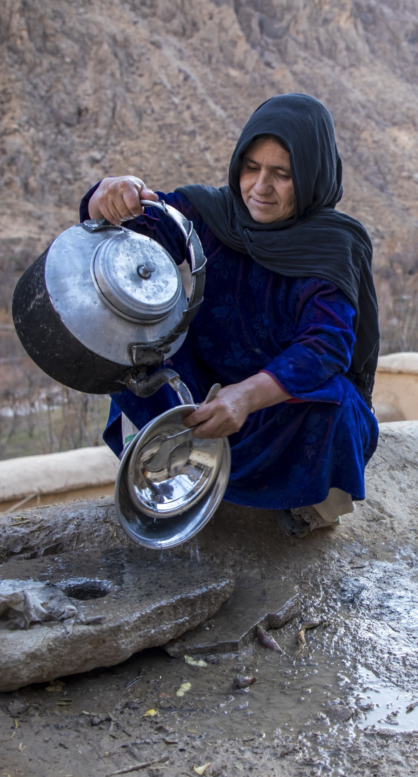 Mahnaz washes her dishes outside her home compound in Duykondi Province, Afghanistan. Action Against Hunger works in this area to manage feeding programs and provide mobile health and nutrition support.