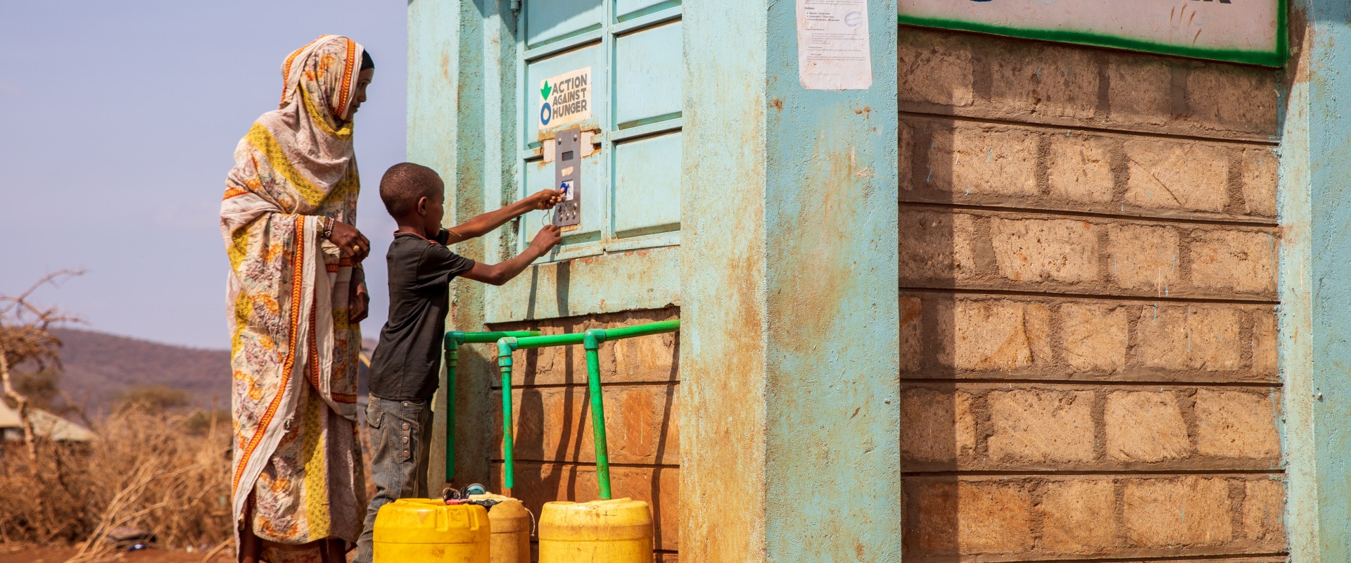 A woman and child bottling water at an Action Against Hunger Smart Tap