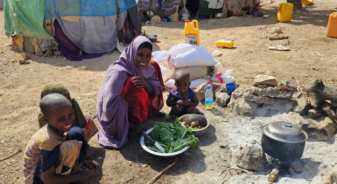 A woman and three children cooking in a displaced community in Somalia.