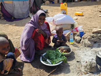 A woman and three children cooking in a displaced community in Somalia.