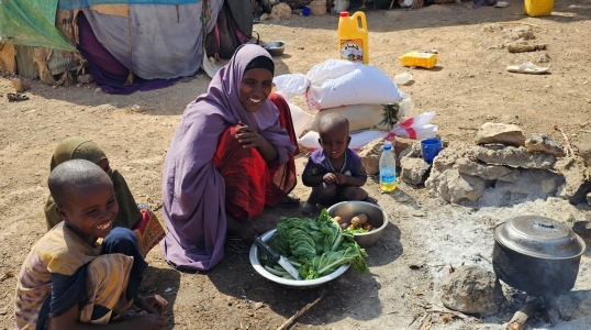 A woman and three children cooking in a displaced community in Somalia.