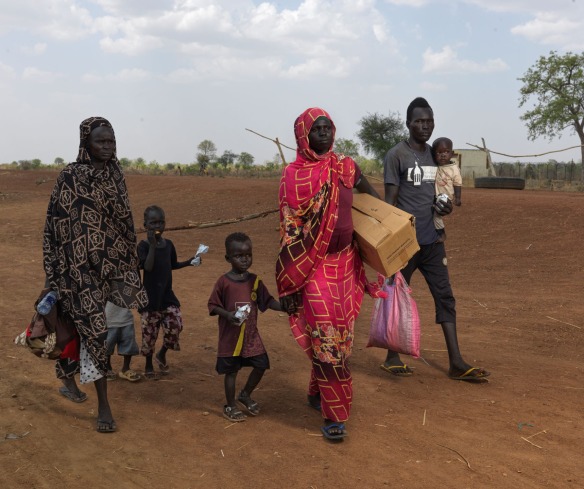 A group of six refugees walk with belongings near the South Sudan border