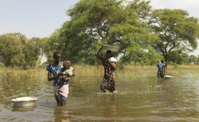 Mothers walk through flooded areas to bring their children to the health center in South Sudan.