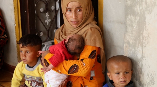 Syrian woman holds three small children.