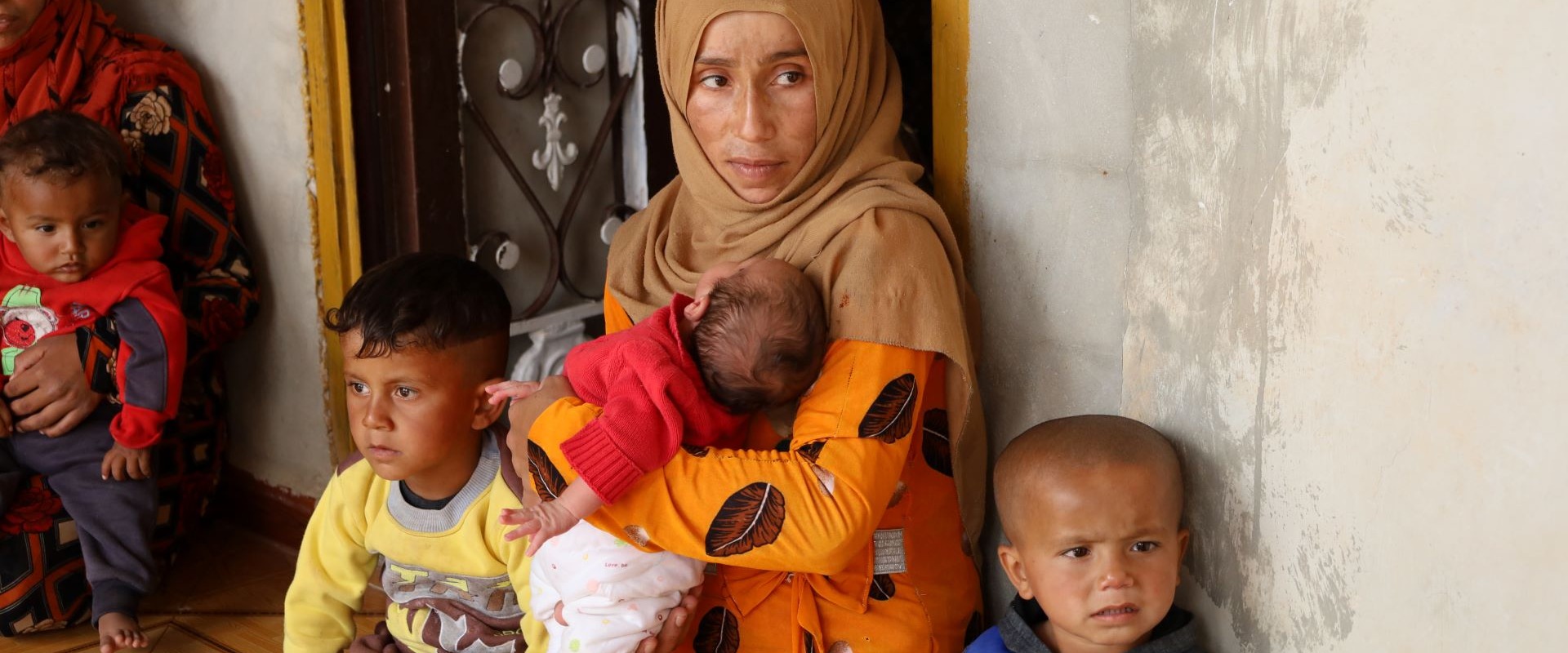 Syrian woman holds three small children.