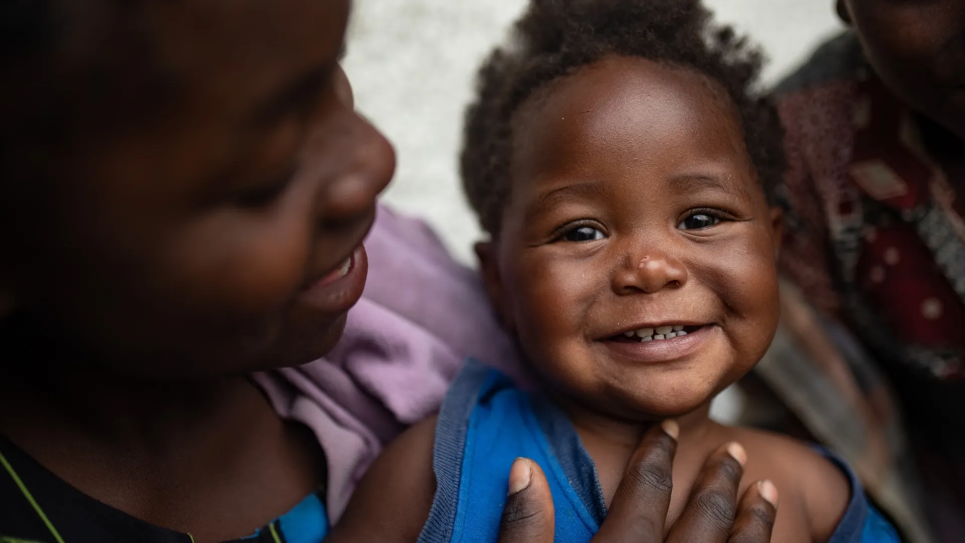 A girl holds her smiling little sister.