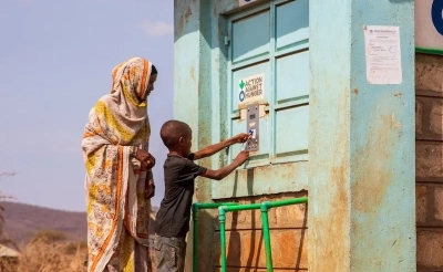 A woman and child bottling water at an Action Against Hunger Smart Tap in Kenya