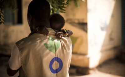 An Action Against Hunger Aid Worker holds a child in his arms in Mali.