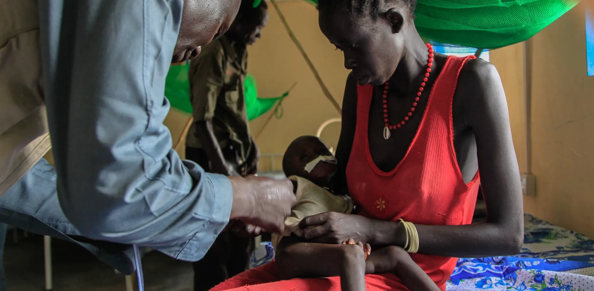 Dr. David Zakaio with one year old Nyankir and her mother at an Action Against Hunger Stabilization Center in Northern Bahr el Ghazal, South Sudan.